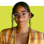 February author Oluwatosin Adeniyi-Miller wearing an orange top. She has pink glasses and is wearing her curly hair in a low side bun.